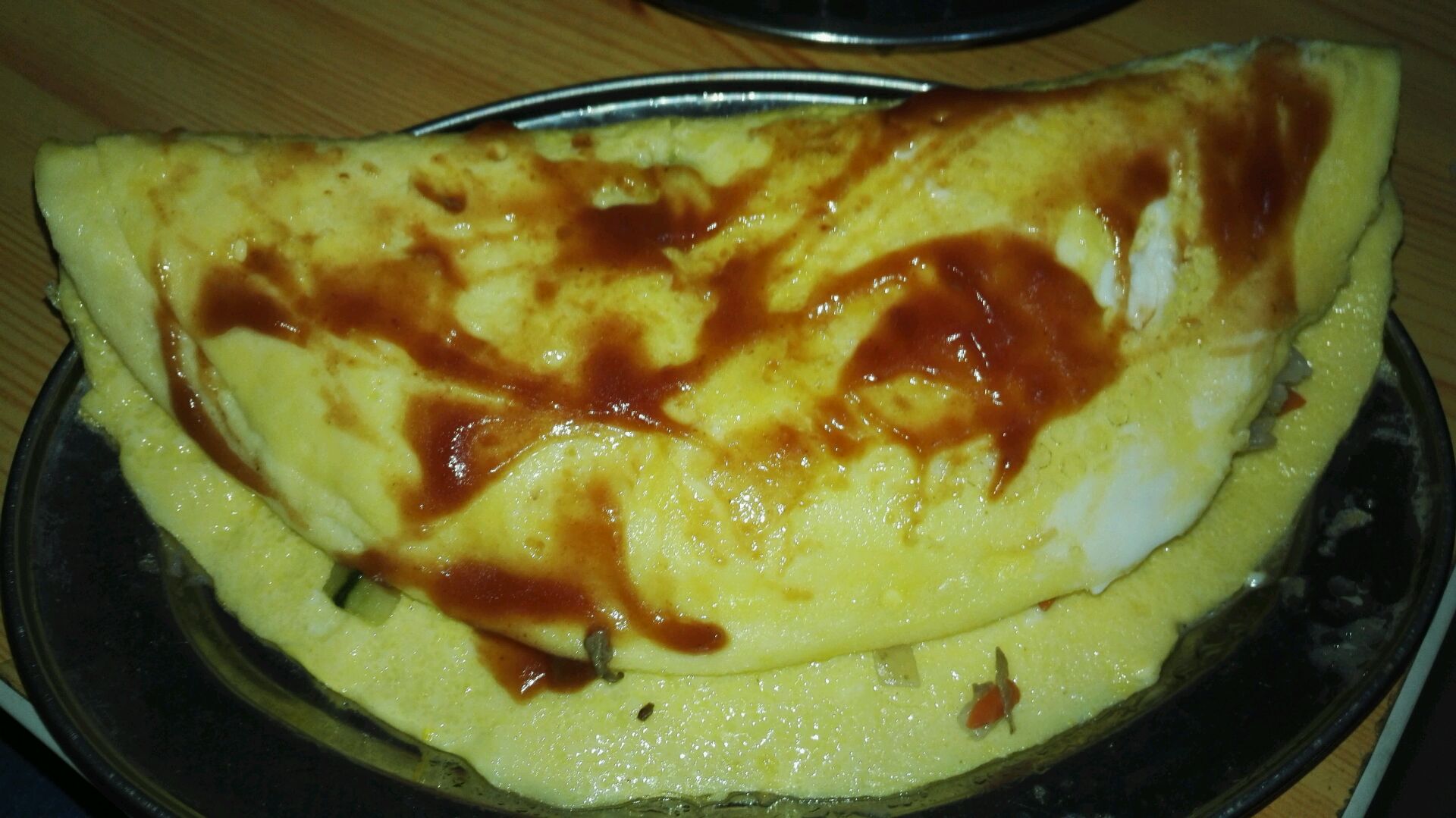 4. 放适量的花生油,让油铺满锅面,然后把搅拌好的蛋液快速导入,开小火煎。期间如果蛋觉得液不均匀,可以通过摇晃平底锅让蛋液流动。看另一面煎得差不多了,就翻面。一定要小心,火候也要注意。第四个步骤的图和第五个步骤的图就是正反两面的效果。