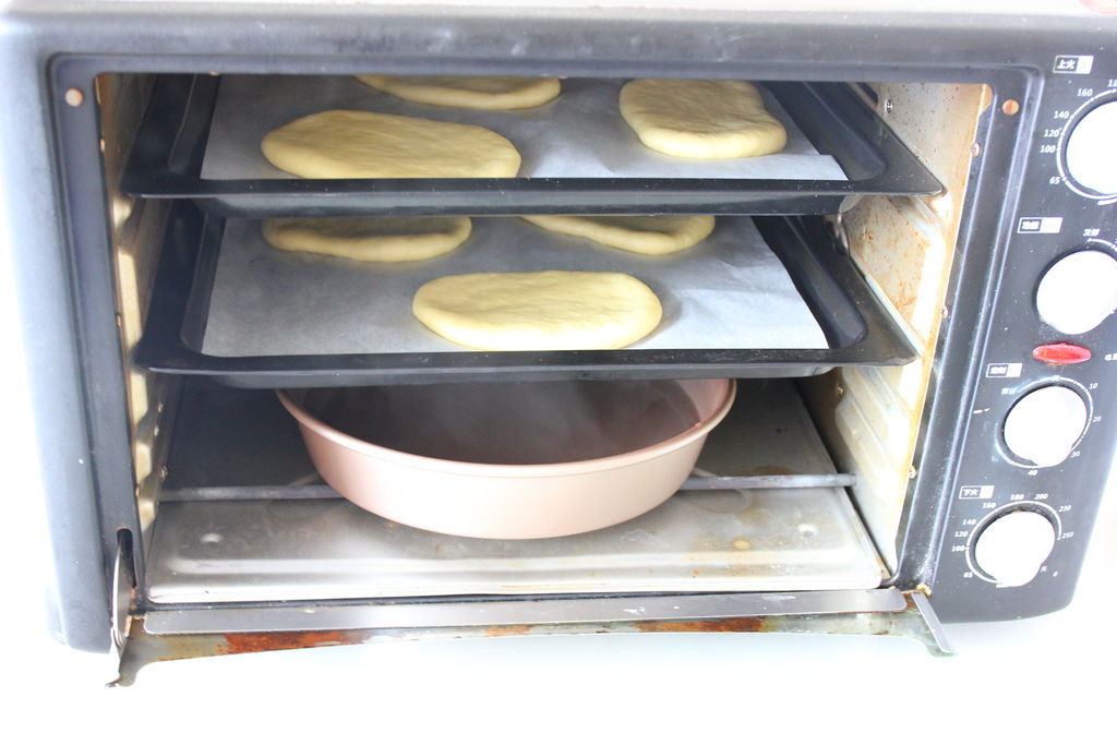 把烤盘放进烤箱里,底下放盆热水,关上烤箱门,不开火进行第二次发酵