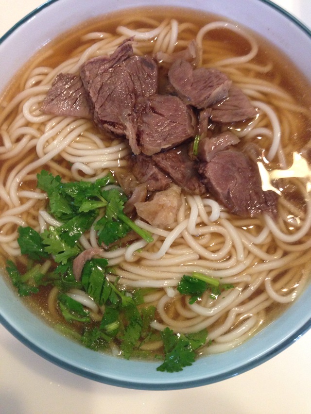 牛腱切片,香菜切末,盛一碗牛肉汤,捞出煮好的面条入碗,一碗香气扑鼻