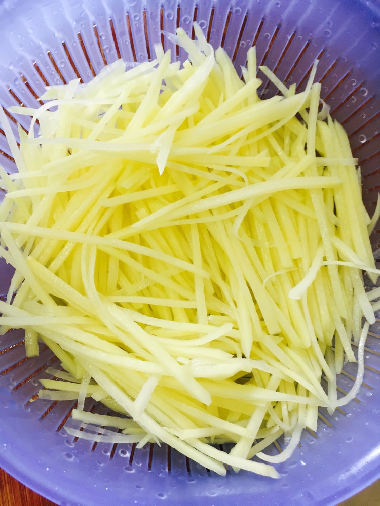 将切好的土豆丝洗掉淀粉,然后用漏斗沥干.