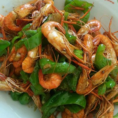 锅热油,放入蒜入味,倒入青椒略炒,倒入虾翻炒,加入盐,鸡精,料酒,翻锅