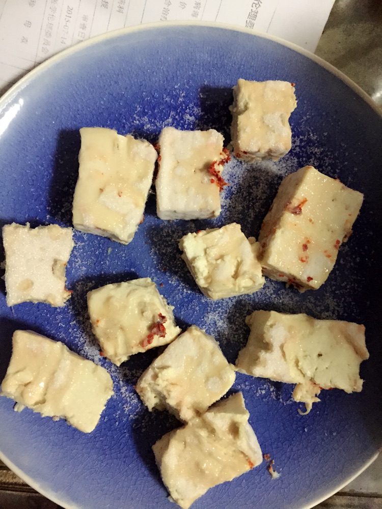 放在稻草上发酵好的豆腐取出来,放在盘子中,先薄薄洒上一层盐.