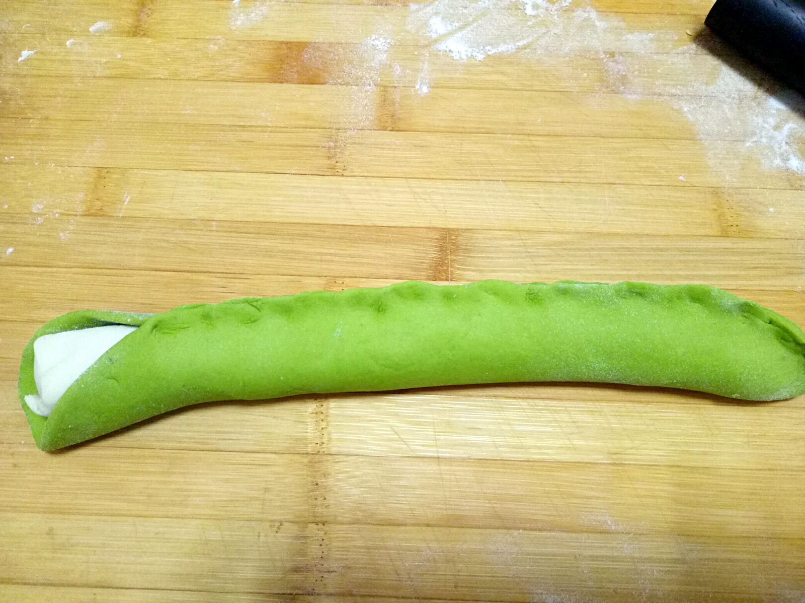 绿色面片把白色粗面条包裹起来,捏紧,两头都捏紧.