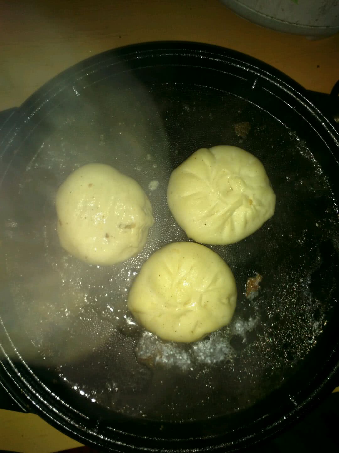 电饼铛放油适量,包子放上,等到包子底金黄倒入开水,倒满电饼铛(包子