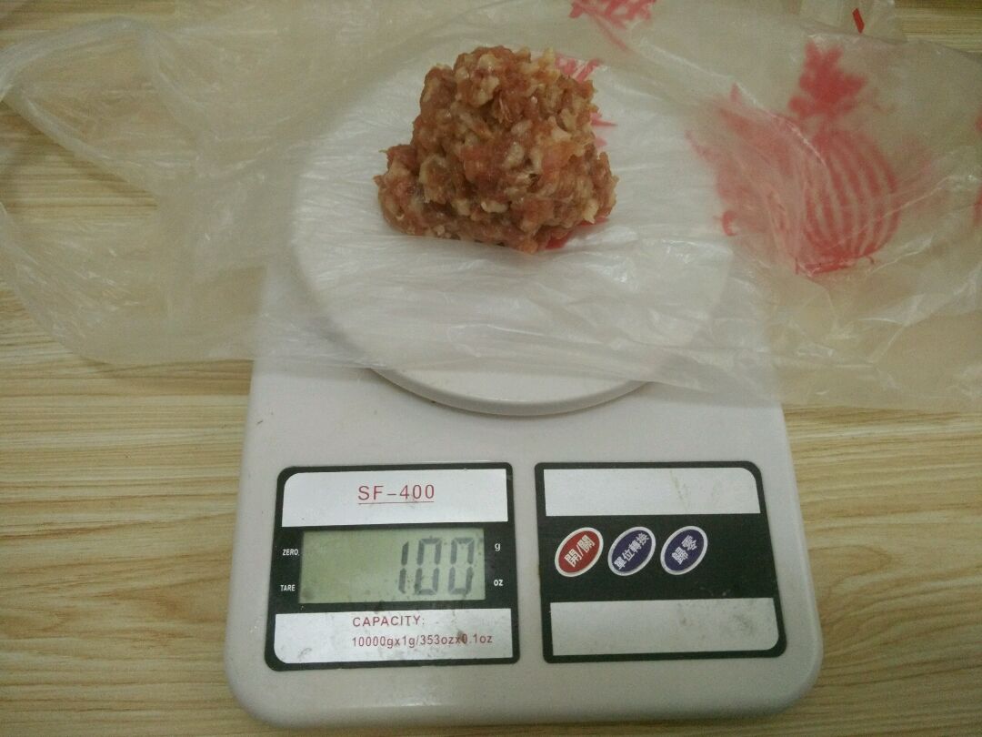 电子秤上垫上薄纸或者塑料袋,每次称量100g的拌好的绞肉