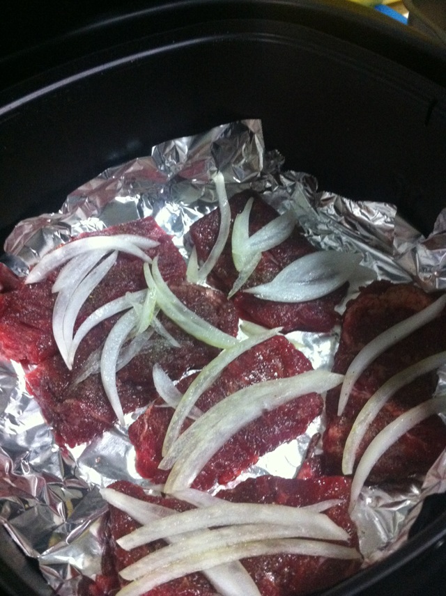 烤篮里铺锡纸,放入腌好入味的牛肉,再撒一些洋葱丝