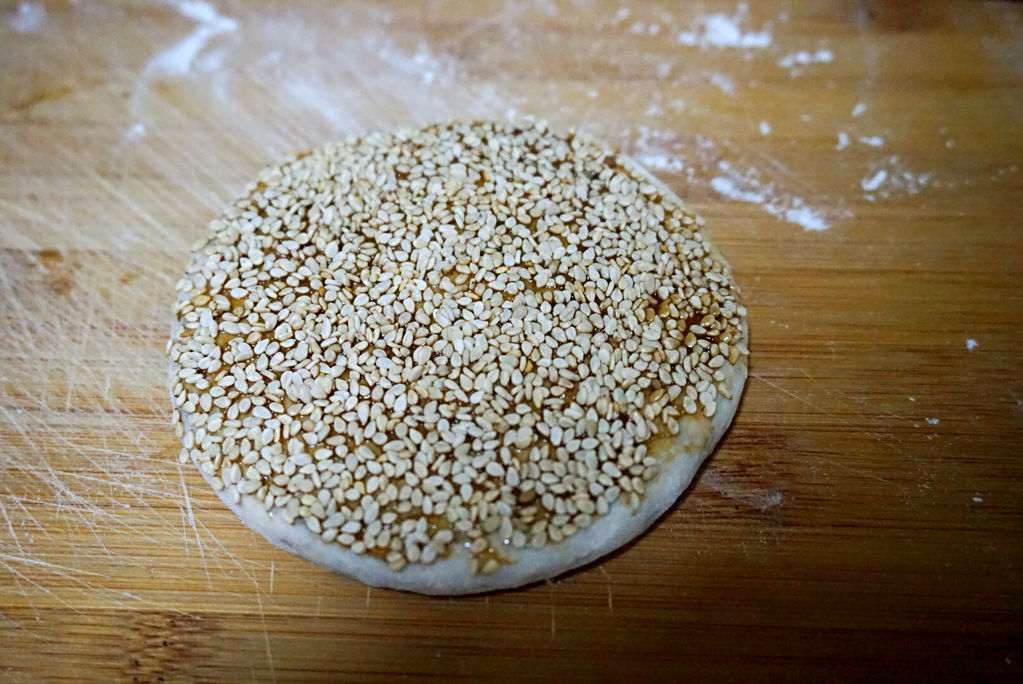 然后在圆饼倒扣在芝麻堆里压一下,使得圆饼表面沾满白芝麻.