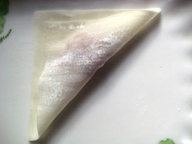 将云吞皮一角沾水,然后对折,形成一个三角形