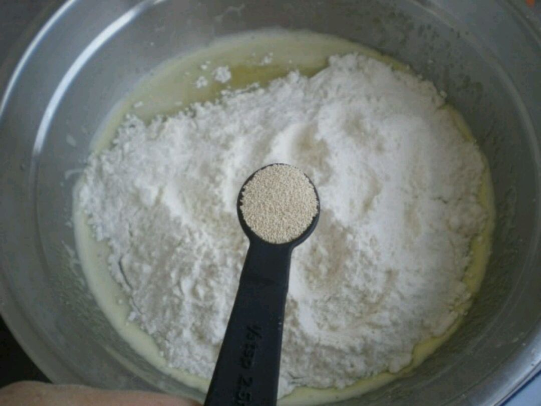 在蛋液里放高筋粉,面粉上撒上酵母粉