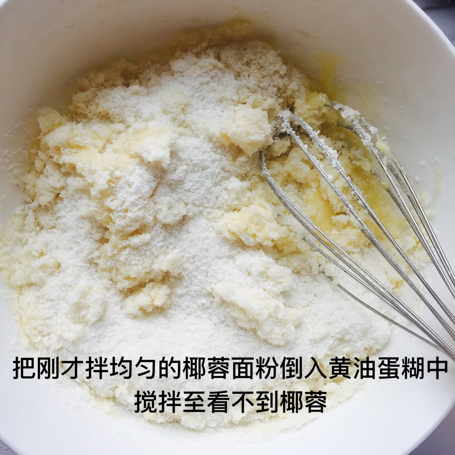 再把刚才拌均匀的椰蓉面粉倒入黄油蛋糊中搅拌均匀