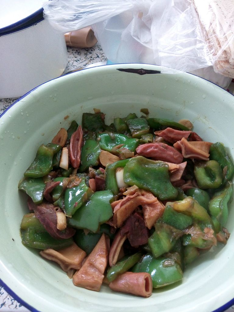 油热后,放入葱和蒜炒出香味,放入青椒,快熟时加味达美和盐,放入猪杂