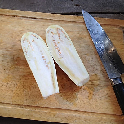 2.茄子用刀竖向对半切开,并在切面上用刀尖划几刀,方便入味