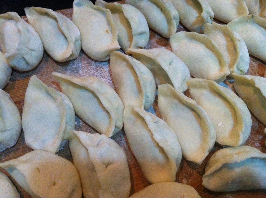 包饺子;取圆皮中间放上馅料,然后对折成半月形,先捏中间,再捏两边