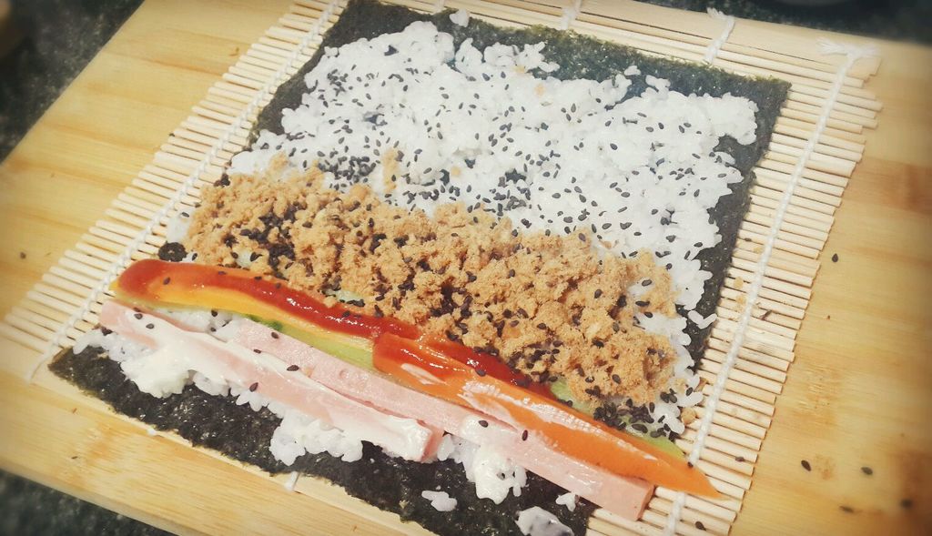 竹帘上铺上海苔,再铺上寿司米(比较粘,建议用小铁勺铺)放上火腿肠,胡