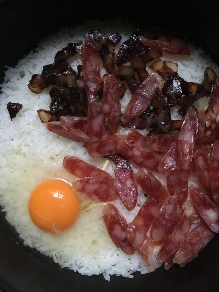 铺上切好的腊肠,腊肉,在边上敲个鸡蛋下去,盖好盖子,取消保温后选择