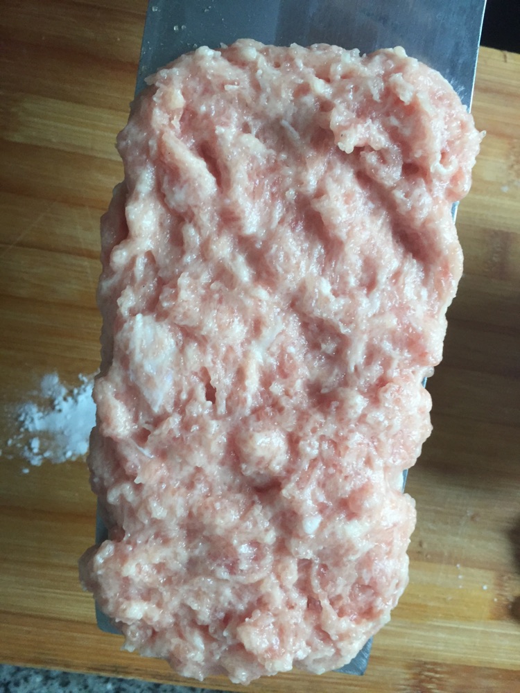 把肉泥摊在刀上,一片片下锅