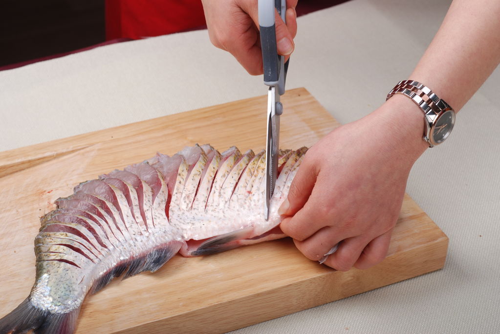 3,为更均匀码放盘中更漂亮,用剪刀将切好的连刀鱼,剪到鱼肚边缘(切忌