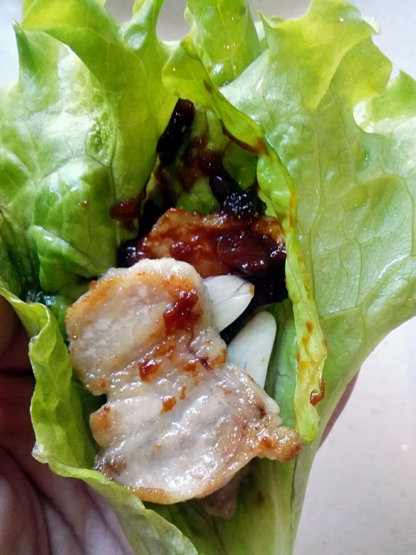 将生菜叶撕成小片,依次放入五花肉,生蒜片,涂抹豆瓣酱